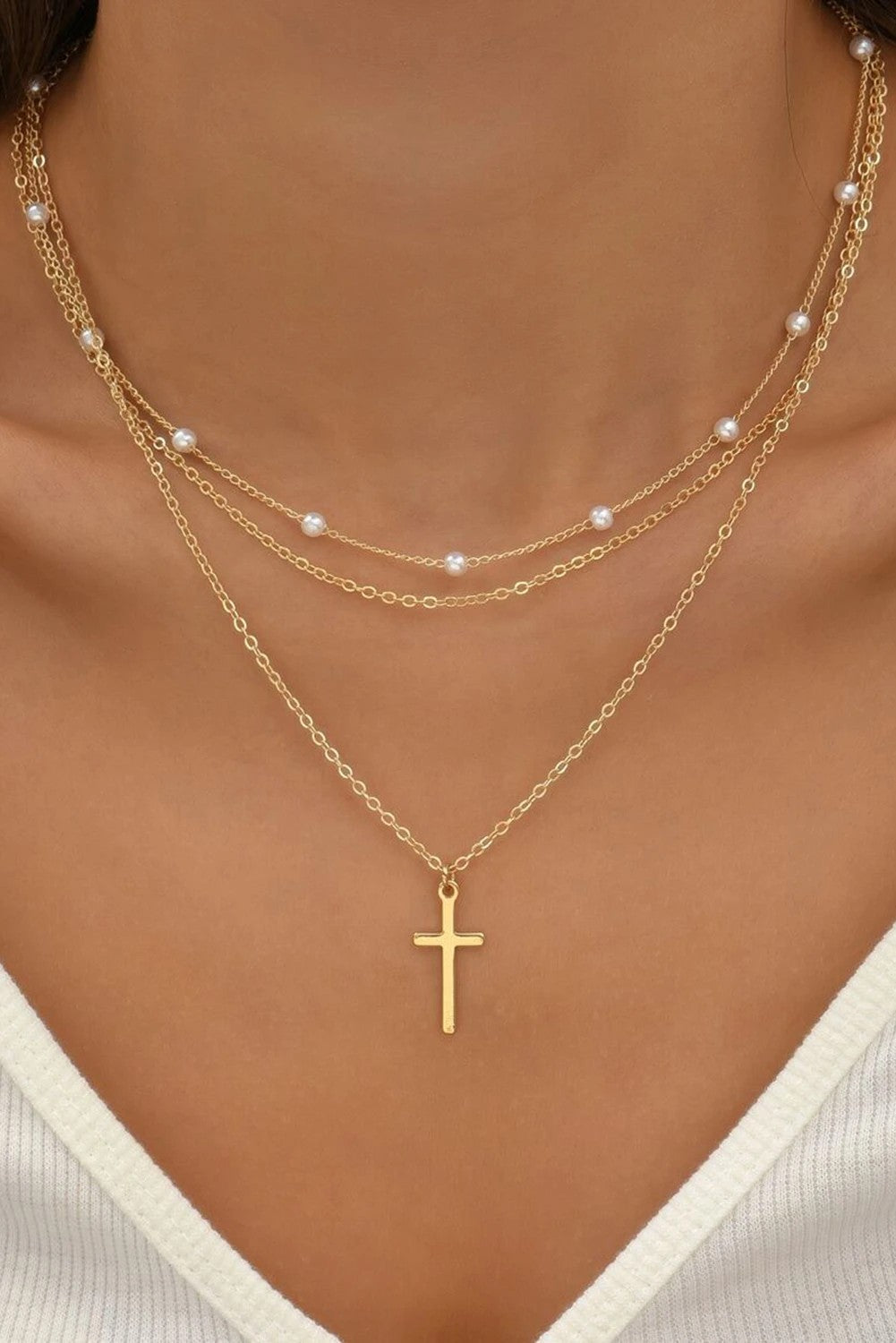 Woman wearing a gold layered cross necklace with delicate beaded chain Christian jewelry from Birkland Boutique faith-based boutique.