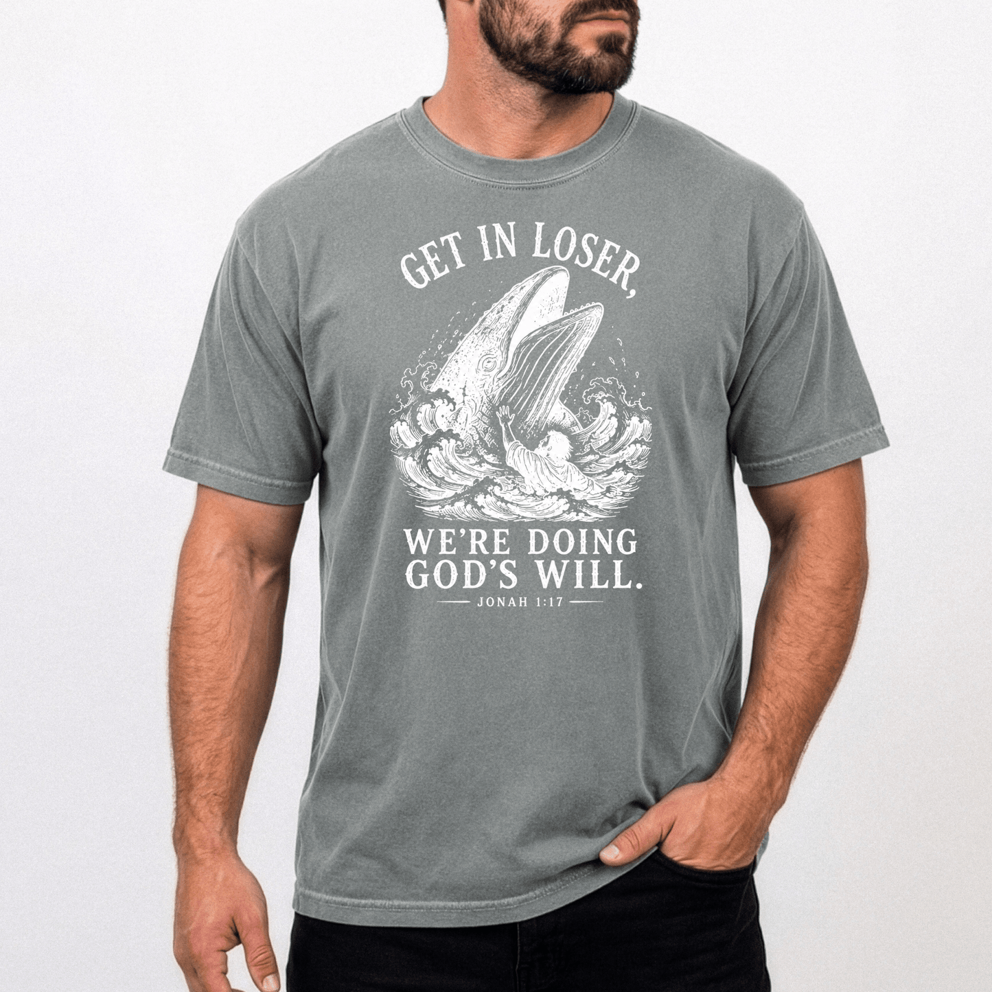 Male model wearing the Get In Loser Jonah 1:17 Christian graphic tee featuring Jonah and the great fish on a gray Comfort Colors unisex shirt.