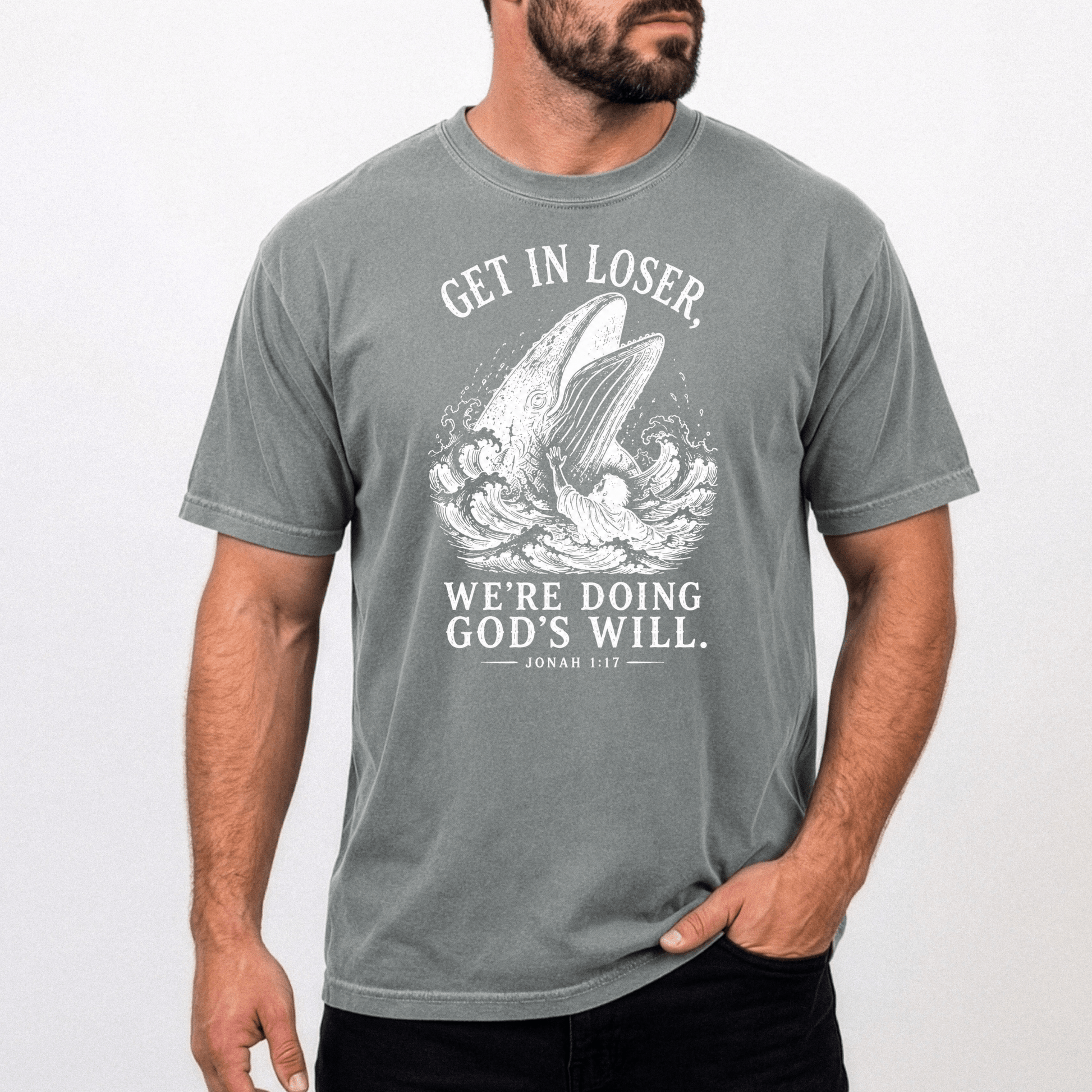 Male model wearing the Get In Loser Jonah 1:17 Christian graphic tee featuring Jonah and the great fish on a gray Comfort Colors unisex shirt.