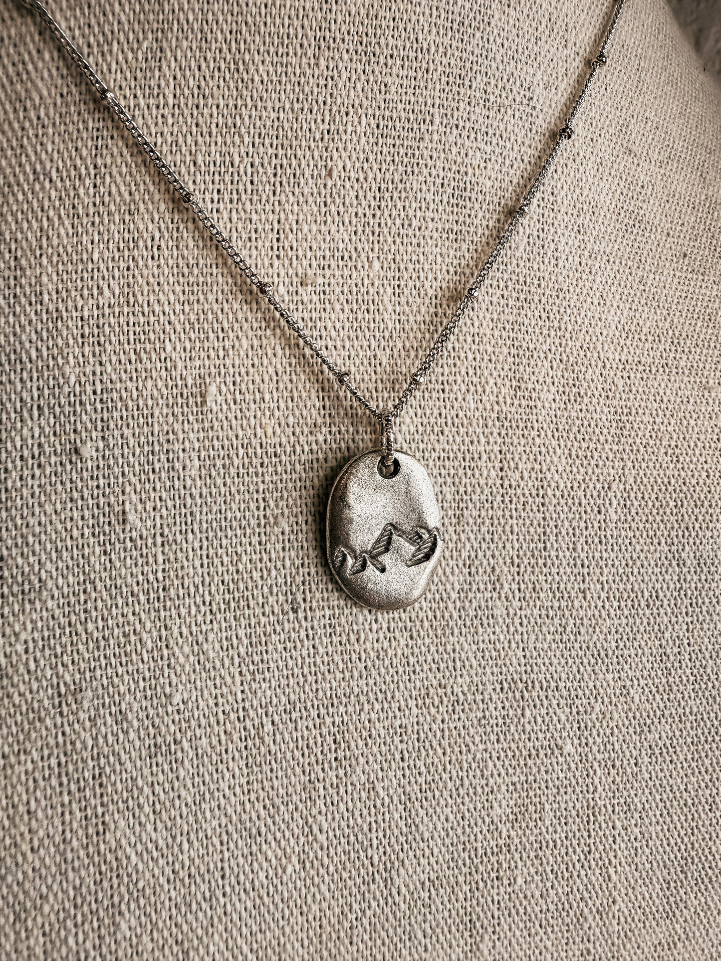Hand-stamped silver Moving Mountains necklace on display at Birkland Boutique in Deer Park, WA