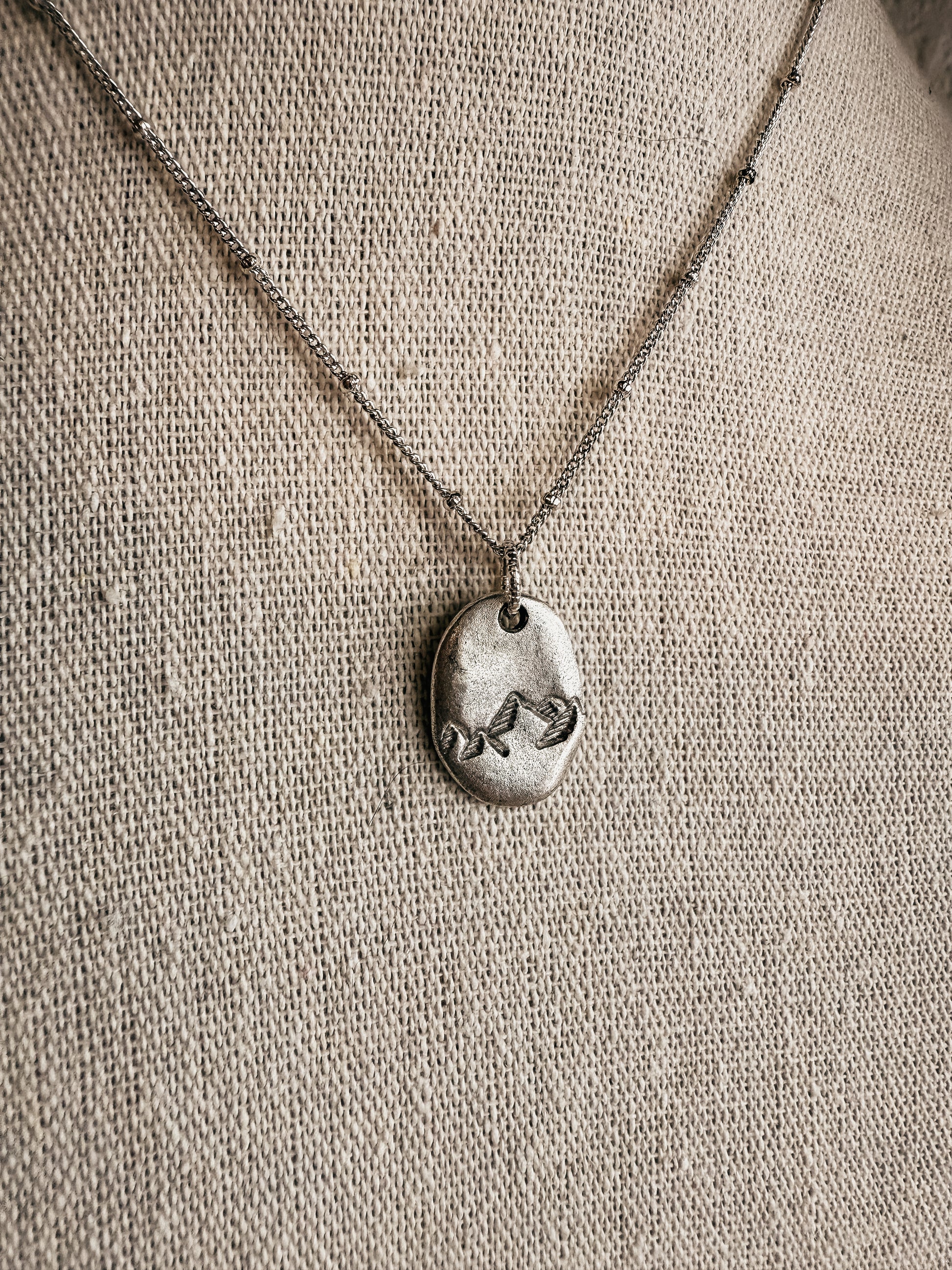 Hand-stamped silver Moving Mountains necklace on display at Birkland Boutique in Deer Park, WA