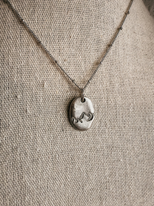 Hand-stamped silver Moving Mountains necklace on display at Birkland Boutique in Deer Park, WA